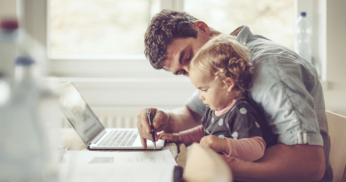 A white man and toddler sit at the table with a laptop