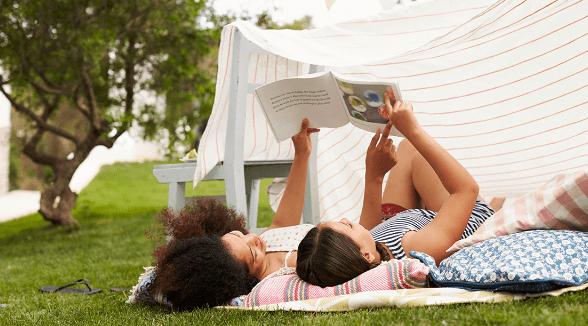 mom and daughter laying outside looking at a book