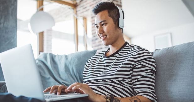 young man wearing headphones working on laptop